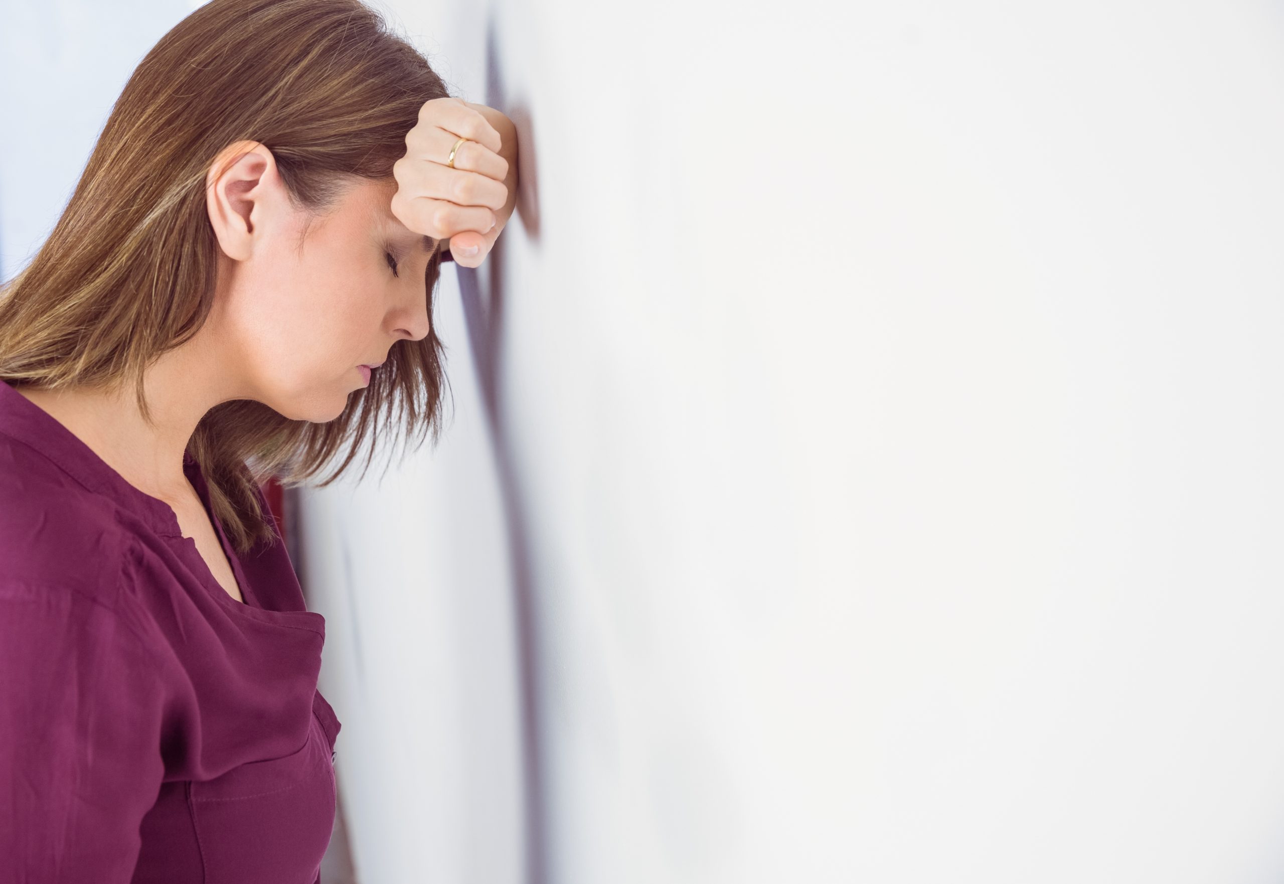 Depressed woman leaning her head against a wall